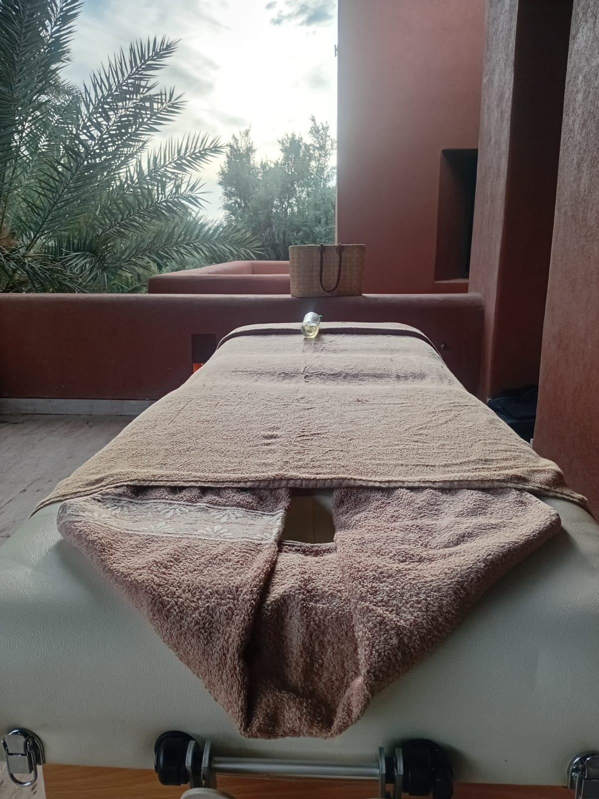 Table de massage installée en terrasse dans un riad à Marrakech, entourée de palmiers, avant une séance M&M SPA