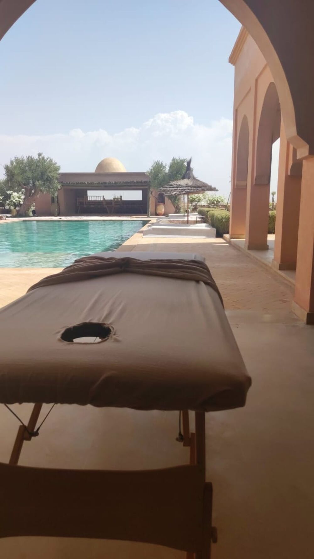 Table de massage installée en terrasse au bord d'une piscine, dans une villa à Marrakech