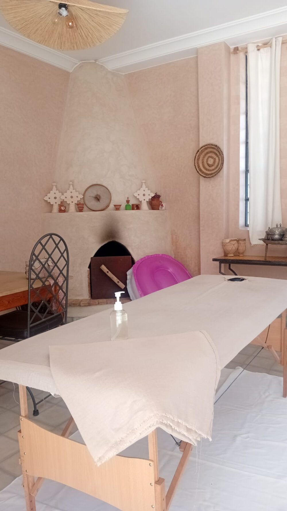 Salle de soin en tadelakt avec cheminée traditionnelle marocaine, table de massage installée pour une séance M&M SPA