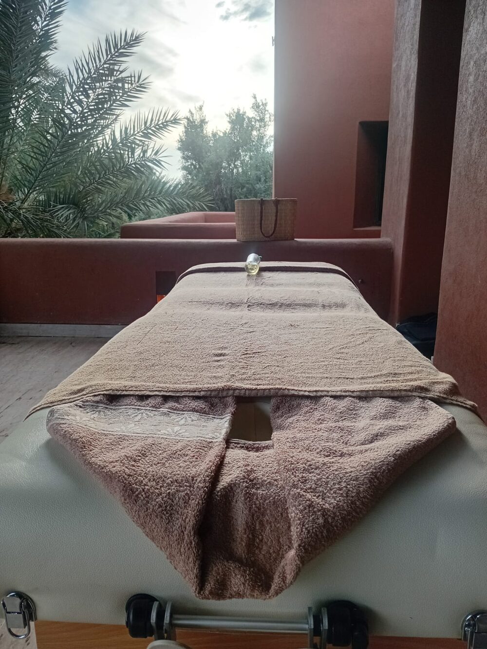 Table de massage installée en extérieur, sous les palmiers, dans un riad à Marrakech